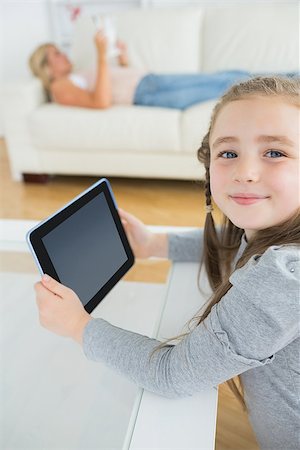 Smiling girl using tablet computer while mother is reading the newspaper on the couch Stock Photo - Budget Royalty-Free & Subscription, Code: 400-06882154