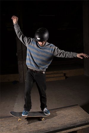 simsearch:6109-06781429,k - Skater wearing helmet doing manual trick on manual pad in skate park Foto de stock - Royalty-Free Super Valor e Assinatura, Número: 400-06882646