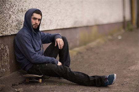 simsearch:6109-06781429,k - Skater taking a break outside the skate park and looking at camera sitting on his board with hood up Foto de stock - Royalty-Free Super Valor e Assinatura, Número: 400-06882652