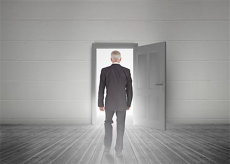 Businessman walking towards door showing light in a dull grey room Stock Photo - Budget Royalty-Free & Subscription, Code: 400-06882682