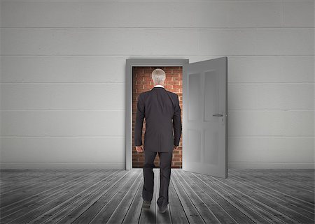 Businessman walking towards door open but blocked by red brick wall in a dull grey room Stock Photo - Budget Royalty-Free & Subscription, Code: 400-06882683