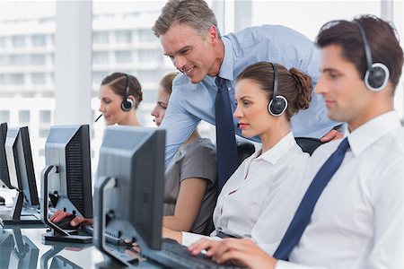 simsearch:400-03985399,k - Smiling manager helping call centre agent with a headset Photographie de stock - Aubaine LD & Abonnement, Code: 400-06882875