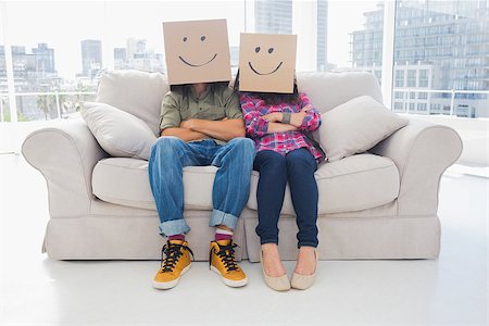 Silly employees with arms folded wearing boxes on their heads with smiley faces on a couch Stock Photo - Budget Royalty-Free & Subscription, Code: 400-06883051