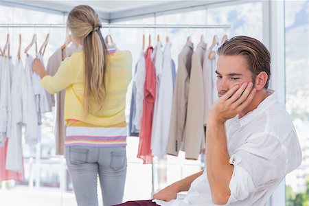 Bored man while his girlfriend is shopping in a boutique Stock Photo - Budget Royalty-Free & Subscription, Code: 400-06883212