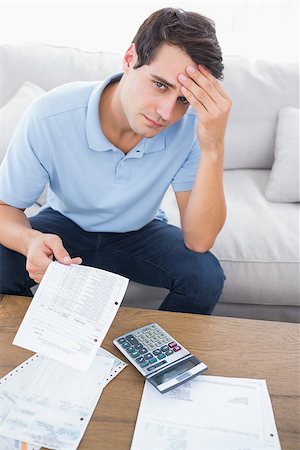 simsearch:400-07333928,k - Fearful man doing his accounts with a calculator sat on a couch Stock Photo - Budget Royalty-Free & Subscription, Code: 400-06890004