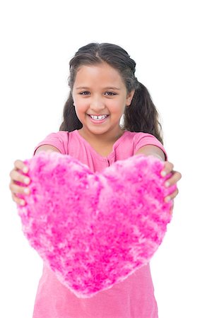 simsearch:400-06885115,k - Smiling little girl showing cushion in the shape of a heart on white background Photographie de stock - Aubaine LD & Abonnement, Code: 400-06890119