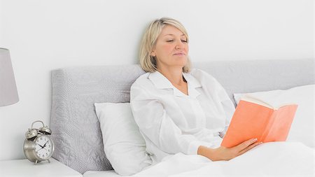 simsearch:400-06891126,k - Blonde woman sitting in bed reading orange book at home Stock Photo - Budget Royalty-Free & Subscription, Code: 400-06891102