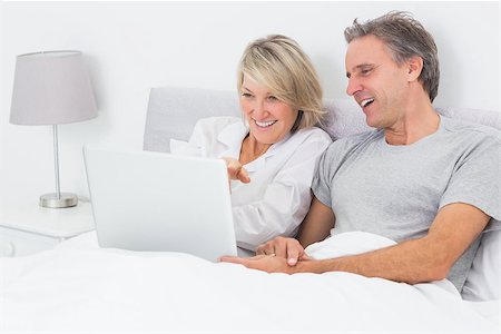 simsearch:400-06891122,k - Happy couple using laptop in bed together at home Photographie de stock - Aubaine LD & Abonnement, Code: 400-06891114