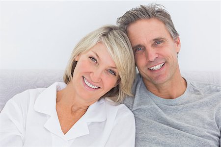 simsearch:400-06891122,k - Cheerful couple in bed smiling at camera Photographie de stock - Aubaine LD & Abonnement, Code: 400-06891112