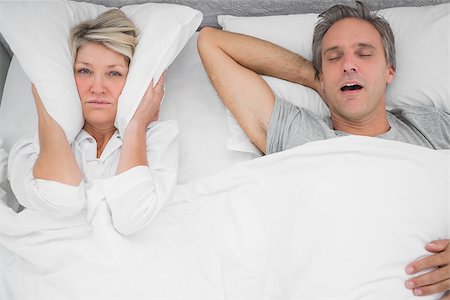 snoring couple - Man snoring loudly as partner blocks her ears at home in bedroom Photographie de stock - Aubaine LD & Abonnement, Code: 400-06891128