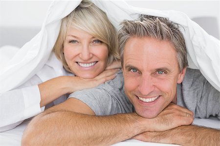 simsearch:400-06891122,k - Couple smiling under the covers at home in bed Photographie de stock - Aubaine LD & Abonnement, Code: 400-06891154