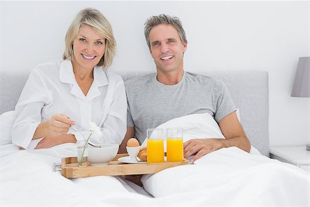 simsearch:400-06891122,k - Happy couple having breakfast in bed and smiling at the camera Photographie de stock - Aubaine LD & Abonnement, Code: 400-06891160