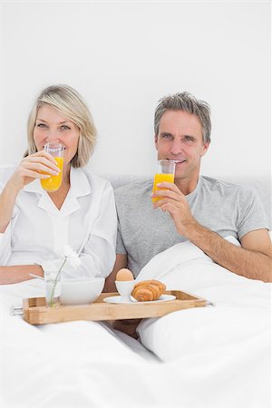 simsearch:400-06891122,k - Couple having orange juice at breakfast in bed at home in bedroom Photographie de stock - Aubaine LD & Abonnement, Code: 400-06891163
