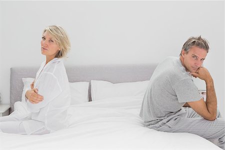 simsearch:400-06891126,k - Couple sitting on opposite sides of bed looking at camera after a fight Stock Photo - Budget Royalty-Free & Subscription, Code: 400-06891188