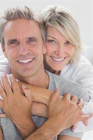 simsearch:400-06891122,k - Hugging couple smiling at camera at home in bedroom Photographie de stock - Aubaine LD & Abonnement, Code: 400-06891194
