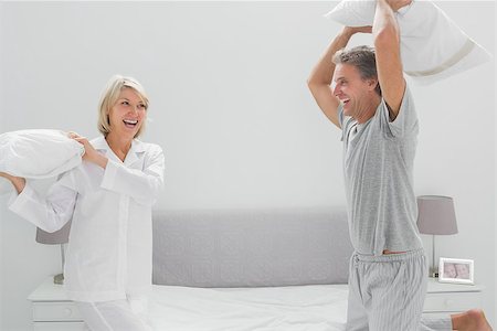 simsearch:400-06891122,k - Laughing couple having a pillow fight at home on bed Photographie de stock - Aubaine LD & Abonnement, Code: 400-06891208