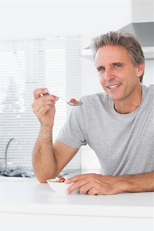 Cheerful man having cereal for breakfast in kitchen at home smiling at camera Stock Photo - Budget Royalty-Free & Subscription, Code: 400-06891220