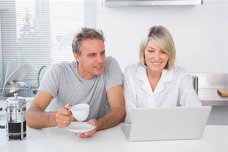 Happy couple using laptop in the morning sitting at kitchen counter Stock Photo - Budget Royalty-Free & Subscription, Code: 400-06891257