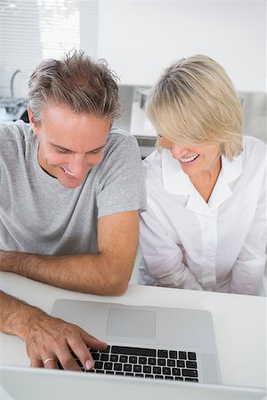Happy couple using their laptop in the morning sitting at kitchen counter Stock Photo - Budget Royalty-Free & Subscription, Code: 400-06891260