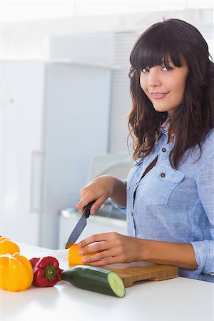 simsearch:400-06891385,k - Pretty brunette chopping pepper at kitchen counter Stock Photo - Budget Royalty-Free & Subscription, Code: 400-06891387