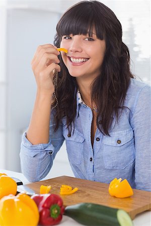 simsearch:400-06891385,k - Pretty brunette holding piece of pepper at home on couch Stock Photo - Budget Royalty-Free & Subscription, Code: 400-06891390