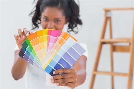 simsearch:400-07834992,k - Excited woman showing colour charts to the camera against a white wall Fotografie stock - Microstock e Abbonamento, Codice: 400-06891491