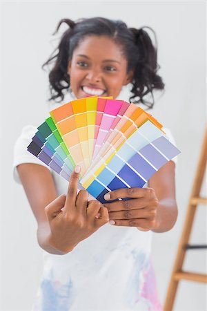 simsearch:400-07834992,k - Excited woman showing colour charts and pointing against a white wall Fotografie stock - Microstock e Abbonamento, Codice: 400-06891492