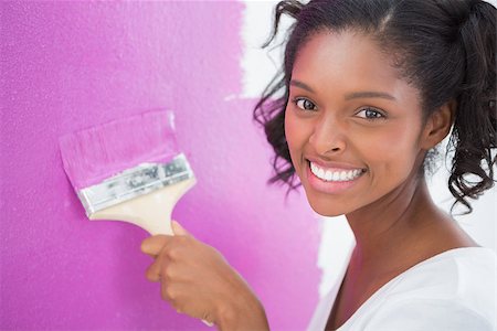 Smiling young woman painting her wall in pink and looking at camera Stock Photo - Budget Royalty-Free & Subscription, Code: 400-06891542