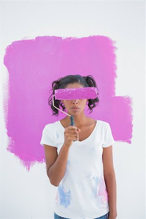 Happy woman holding paintroller over her face against pink paint on a wall Photographie de stock - Aubaine LD & Abonnement, Code: 400-06891556