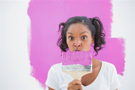 Happy woman making funny face behind paintbrush and looking at camera Photographie de stock - Aubaine LD & Abonnement, Code: 400-06891550