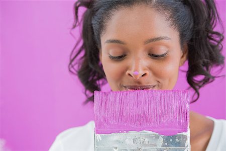 simsearch:400-07834992,k - Cheerful woman holding paintbrush with paint on her nose against a pink wall Fotografie stock - Microstock e Abbonamento, Codice: 400-06891552