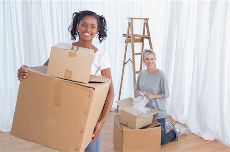 simsearch:400-07834992,k - Young friends unpacking cardboard boxes in their new home and smiling at cameraunpacking Fotografie stock - Microstock e Abbonamento, Codice: 400-06891564