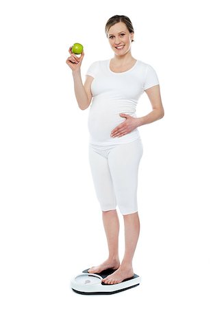 Pregnant woman standing on weighing machine showing fresh juicy green apple Stock Photo - Budget Royalty-Free & Subscription, Code: 400-06914845