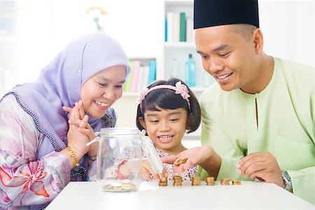 Islamic banking concept. Southeast Asian family counting money at home. Little Malay girl and parents saving money. Muslim father, mother and daughter living lifestyle. Foto de stock - Super Valor sin royalties y Suscripción, Código: 400-06915034