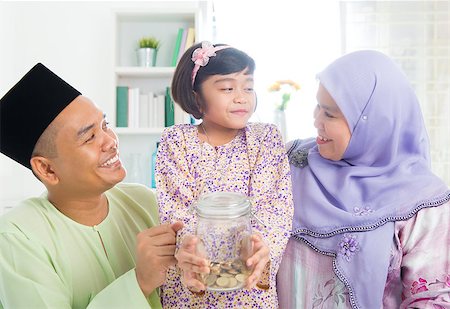 Islamic banking concept. Southeast Asian Malay family saving money at home. Muslim father, mother and daughter living lifestyle. Stock Photo - Budget Royalty-Free & Subscription, Code: 400-06915035