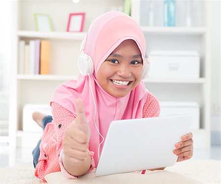 Asian teen listening to music with headphone and thumb up. Southeast Asian teenager at home. Muslim teenage girl living lifestyle. Stock Photo - Budget Royalty-Free & Subscription, Code: 400-06915044