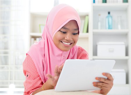 Asian teen using tablet pc computer. Southeast Asian teenager at home. Muslim teenage girl living lifestyle. Stock Photo - Budget Royalty-Free & Subscription, Code: 400-06915045