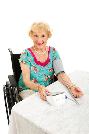 simsearch:400-04419056,k - Beautiful senior woman in wheelchair taking her blood pressure with a home machine.  White background. Foto de stock - Royalty-Free Super Valor e Assinatura, Número: 400-06917338