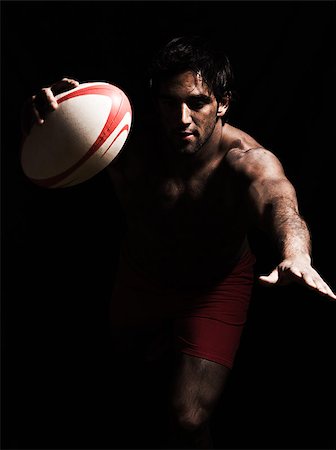 one caucasian sexy topless man scoring touchdown with  a rugby ball on studio black background Stock Photo - Budget Royalty-Free & Subscription, Code: 400-06917858