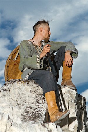 simsearch:877-07460485,k - Knight sitting on a rock with a sword against blue cloudy sky Photographie de stock - Aubaine LD & Abonnement, Code: 400-06919703