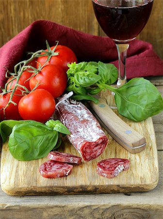 simsearch:400-06063216,k - Still life of delicacy salami, tomatoes and basil -  rustic style Fotografie stock - Microstock e Abbonamento, Codice: 400-06924374