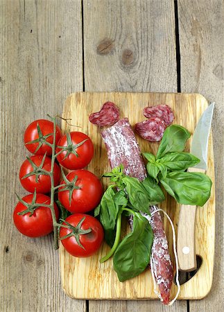 simsearch:400-06063216,k - Still life of delicacy salami, tomatoes and basil -  rustic style Fotografie stock - Microstock e Abbonamento, Codice: 400-06924373