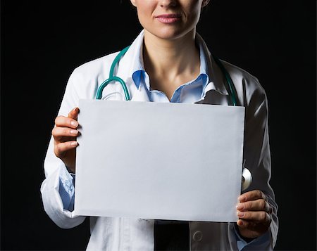 simsearch:400-05745246,k - Closeup on doctor woman showing blank paper sheet isolated on black Photographie de stock - Aubaine LD & Abonnement, Code: 400-06925567