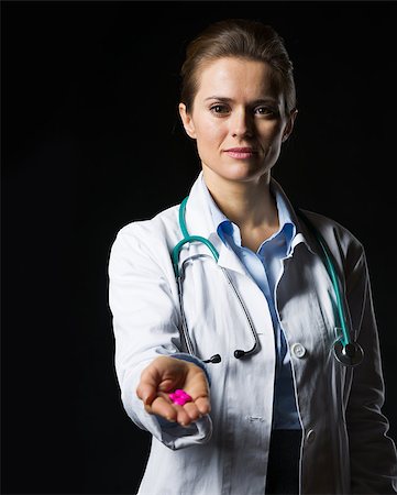 simsearch:400-07099882,k - Doctor woman showing pills isolated on black Photographie de stock - Aubaine LD & Abonnement, Code: 400-06925569