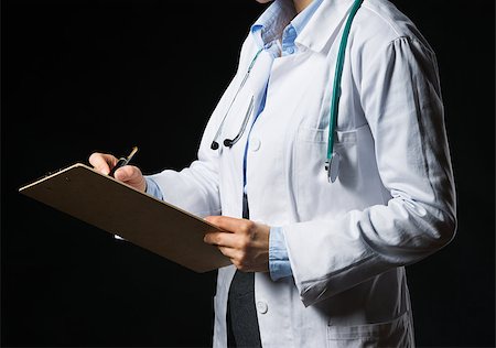 simsearch:400-07099882,k - Closeup on doctor woman writing in clipboard isolated on black Photographie de stock - Aubaine LD & Abonnement, Code: 400-06925574