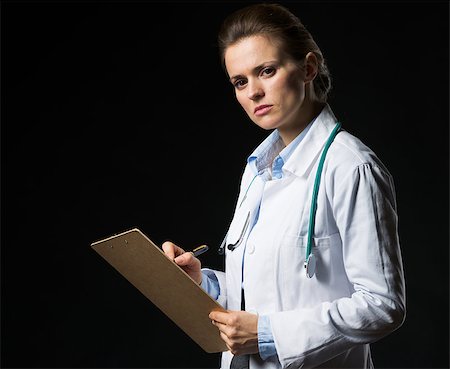 simsearch:400-07099882,k - Doctor woman writing in clipboard isolated on black Photographie de stock - Aubaine LD & Abonnement, Code: 400-06925575