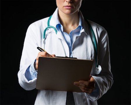 simsearch:400-07099882,k - Closeup on doctor woman writing in clipboard isolated on black Photographie de stock - Aubaine LD & Abonnement, Code: 400-06925572