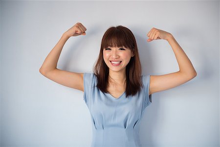 Portrait of funny strong muscle Asian woman smiling wearing blue dress isolated on blue background. Asian female model. Stock Photo - Budget Royalty-Free & Subscription, Code: 400-06928023