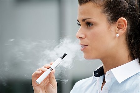 young female smoker smoking e-cigarette outdoors. Head and shoulders, side view Foto de stock - Super Valor sin royalties y Suscripción, Código: 400-06928035