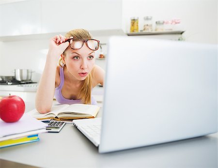 Surprised young woman looking in laptop while studying in kitchen Stock Photo - Budget Royalty-Free & Subscription, Code: 400-06929120